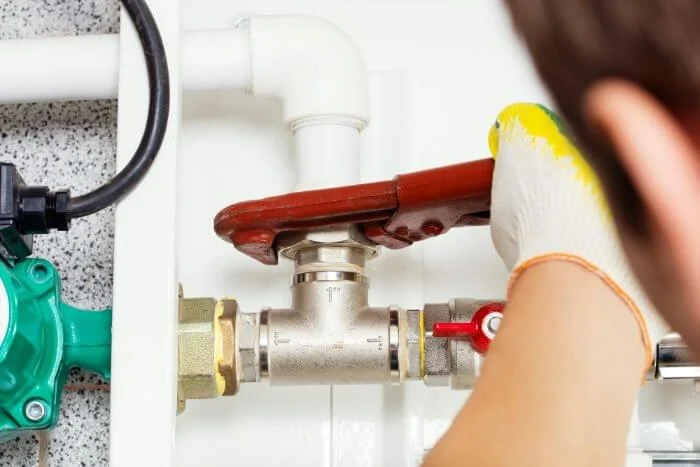 A plumber repairing a pipe under a sink.