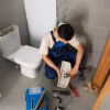 Plumber repairing a toilet in a bathroom in Gilbert, Arizona.